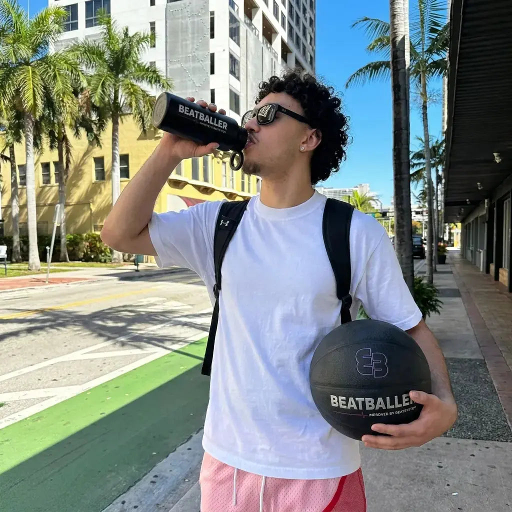 Joueur de basket qui boit avec la gourde Beatballer® en ville, ballon Beatballer® à la main