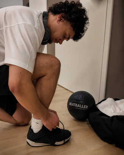 Joueur de basket en préparation avant l’entraînement avec un Beatball® Grip+ posé près de son sac de sport