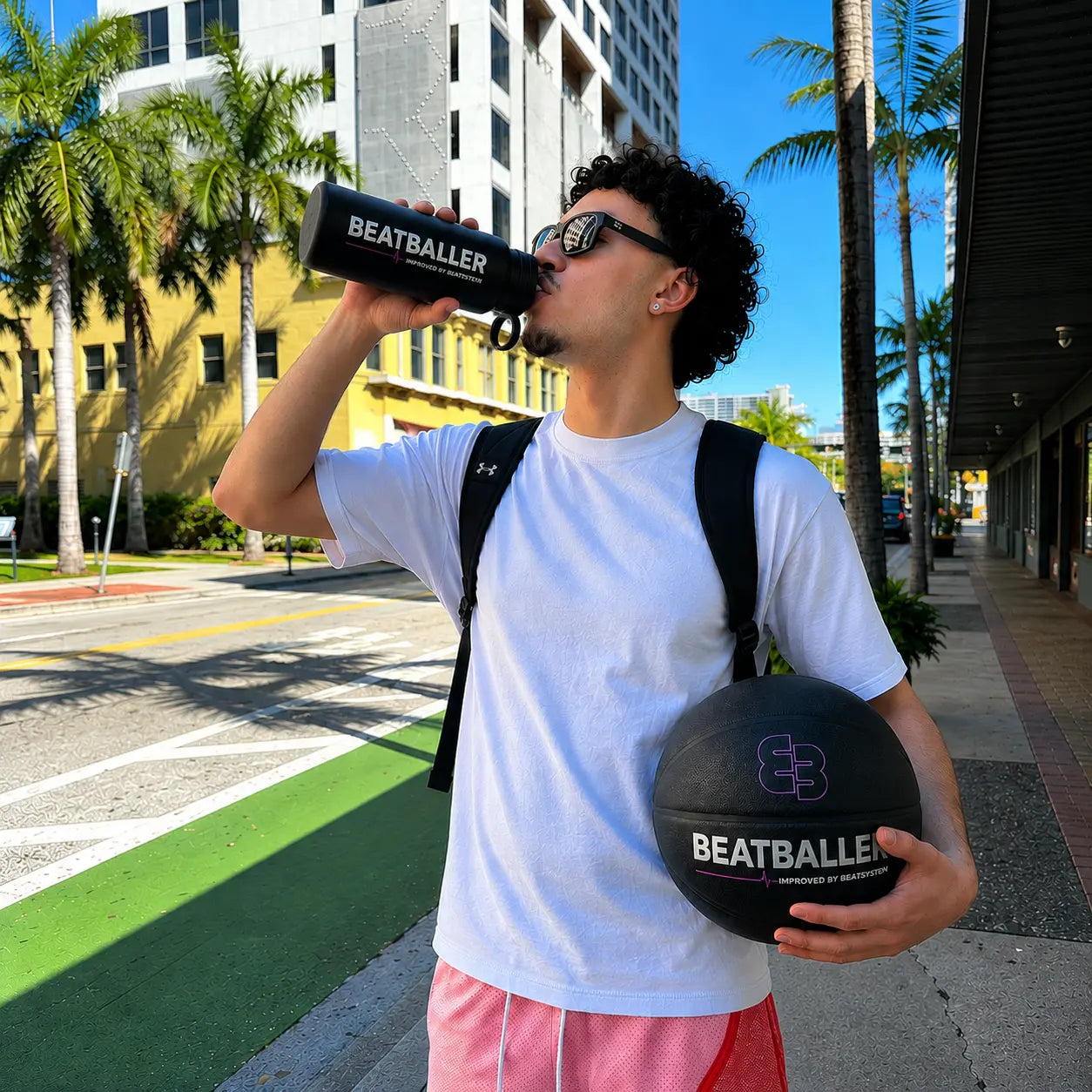 Joueur de basket qui boit avec la gourde Beatballer® en ville, ballon Beatballer® à la main