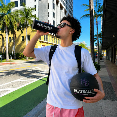 Joueur de basket qui boit avec la gourde Beatballer® en ville, ballon Beatballer® à la main