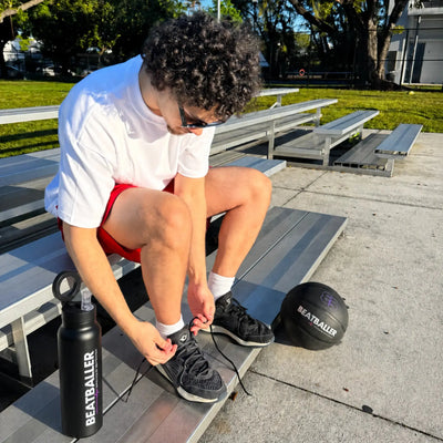 Joueur de basket préparant son entraînement avec une gourde Beatballer® et un ballon Beatballer® sur des gradins